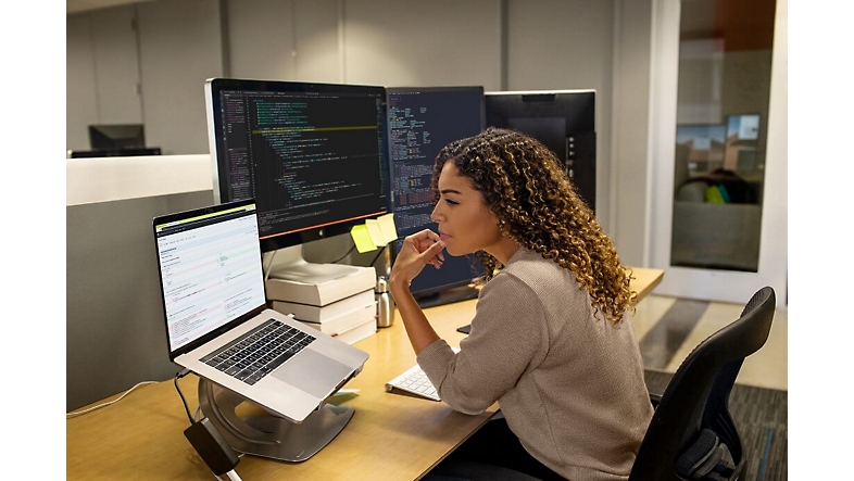 Egy nő, aki a kezével az arcán gondolkodik, miközben a laptopot nézi