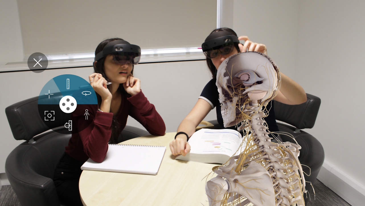 Two people wearing HoloLens 2 and viewing a skeleton in mixed reality.