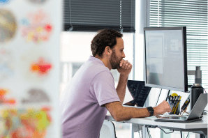 A person looking at a monitor at their desk