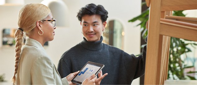 Two persons discussing with one person holding a tablet