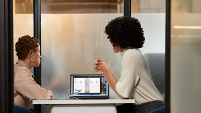 Two people reviewing information together on a laptop during a workplace discussion.