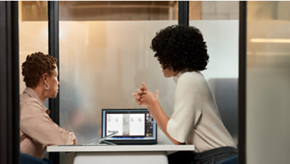 Two people reviewing information together on a laptop during a workplace discussion.