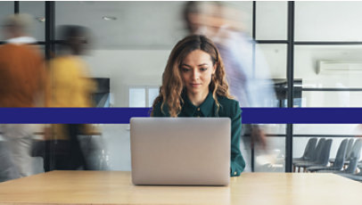 Person working on a laptop in a busy office environment. Image from the IDC white paper.