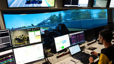 Eine Person, die ein Rennvisual an einem Schreibtisch mit mehreren Bildschirmen programmiert