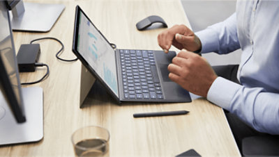 Hände, die ein Tablet verwenden, das mit einer Tastatur verbunden ist.