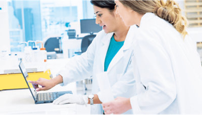 Zwei Gesundheitsexperten, die sich unterhalten und auf einen Laptop schauen.