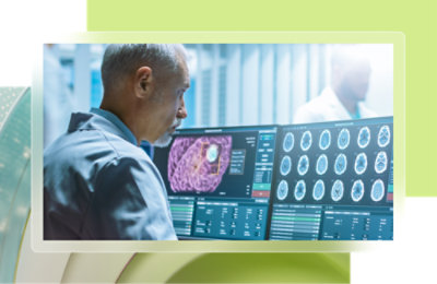 Un homme aux cheveux gris, vêtu d'une chemise bleue, regarde un écran d’ordinateur.