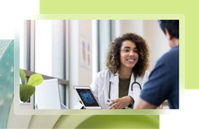 Une femme aux cheveux bouclés portant une blouse blanche et souriant.