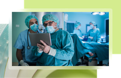 A group of doctors in scrubs and face masks holding a laptop.