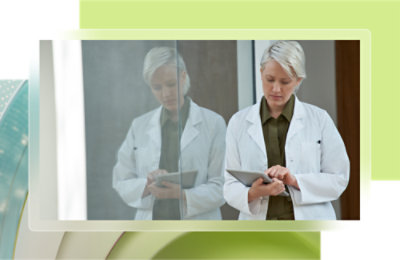 A woman in a white lab coat using a tablet.
