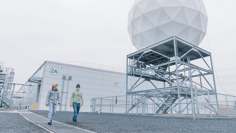 Two people wearing protective masks walking outside of a data storage facility