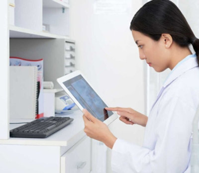 A woman in a lab coat using a tablet.