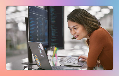 Persoon die op een laptop werkt met code op het scherm in een kantooromgeving.