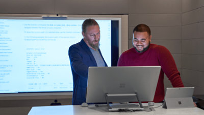 Two people having a conversation over a desktop monitor.