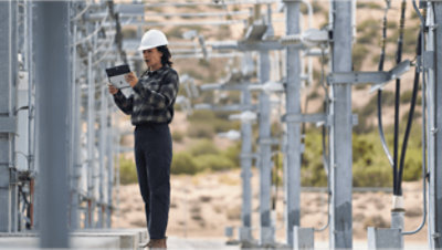 A worker looking at a Surface device while in the field.