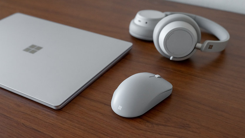 A group of Surface products incuding wireless mouse, a laptop, and a headset.