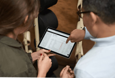 Zwei Personen überprüfen Berichtsdaten in einer Tabelle.