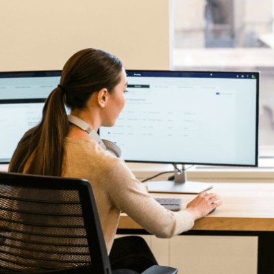 Eine Person sitzt auf einem Stuhl und arbeitet am Schreibtisch.