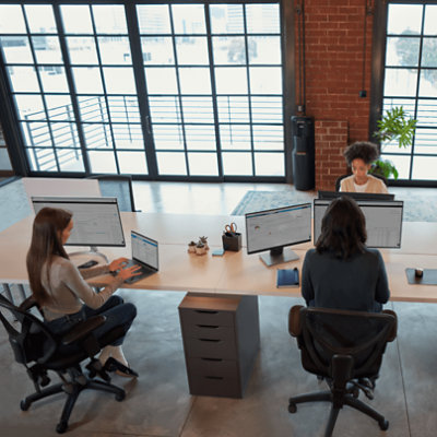 Trois personnes travaillant avec leur ordinateur de bureau et leur ordinateur portable