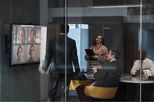 Chamada de vídeo no ecrã com múltiplas pessoas numa sala de reuniões