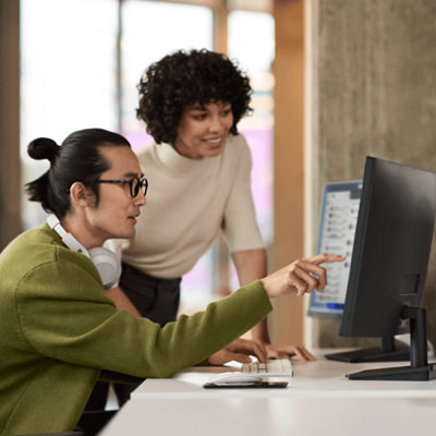 Two people looking in the desktop and one person pointing at screen with finger