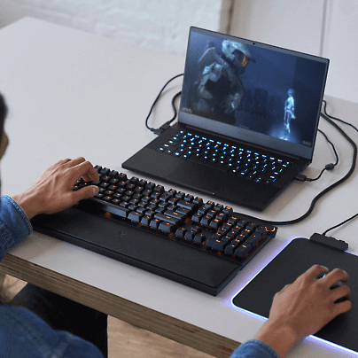 Een persoon die naar het scherm van een laptop kijkt en een extern toetsenbord met muis gebruikt