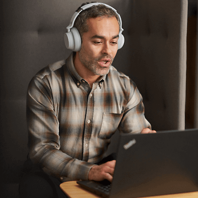 A person talking over laptop using headphones