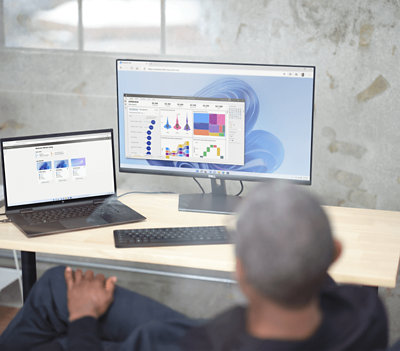 Une personne se détendant sur sa chaise et regardant le tableau de bord sur un moniteur et un ordinateur portable est également présente sur la table