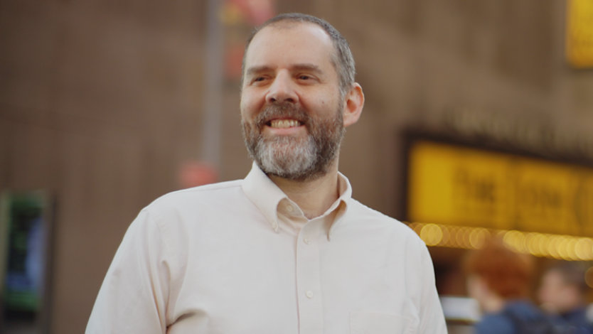 Ein Mann steht in New York City mit dem Broadway im Rücken.