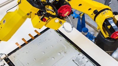 Lengan mekanik sedang membuat pelat logam besar. 