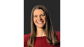 Person wearing a red textured sweater against a plain dark background.