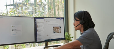Person working at a desk with two computer monitors, one displaying a login screen and the other showing an email inbox.