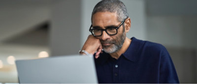 Person in a blue sweater working on a laptop in an office setting.