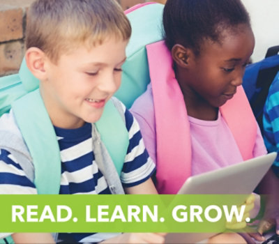 リュックを背負った 2 人の子供が並んで座り、タブレットを使用しています。"READ. LEARN. GROW." という言葉が下部に表示されます。