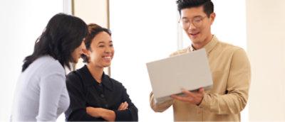 Three individuals in a business setting, one holding and reading from a document to the others.