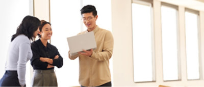 Two individuals engaged in a discussion with a third person holding a document in an office setting.