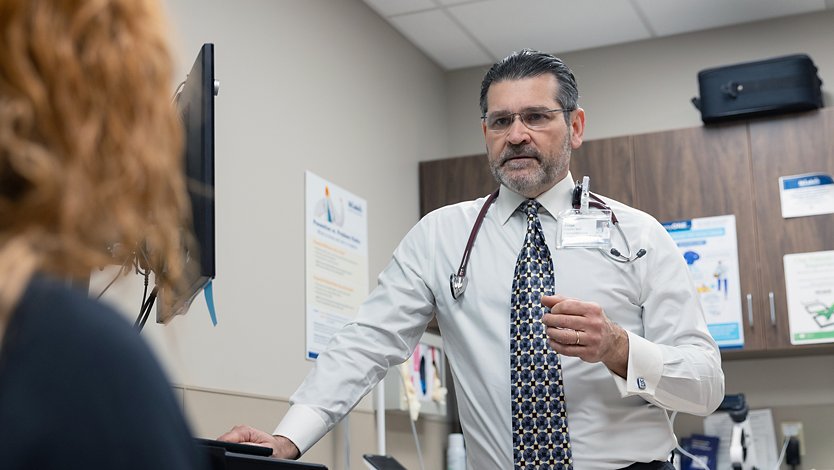 A doctor speaks to a patient in a medical exam room.
